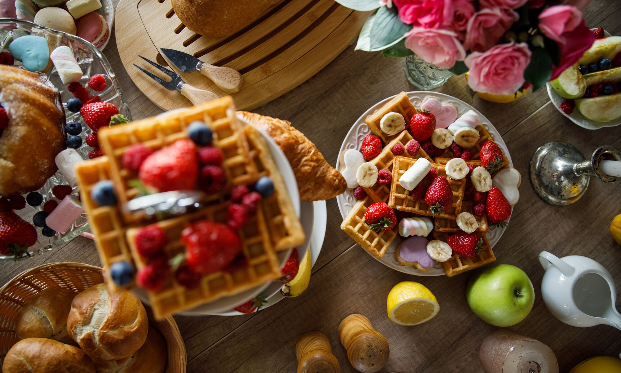 Brunch foods sit on a table including waffles, strawberries, apples, buns, and maple syrup at the Rimrock Resort in Banff National Park.